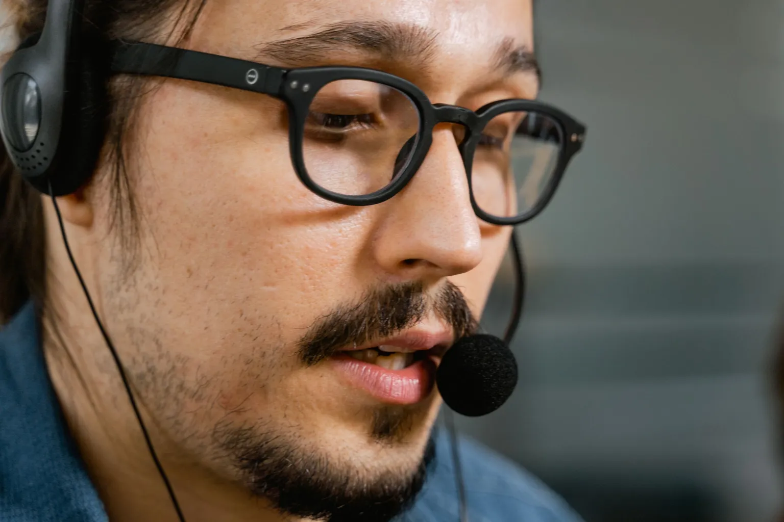 Close-up of a support engineer with glasses talking into a headset microphone